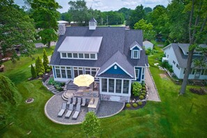 A large house with a spacious patio, a covered seating area, and a well-maintained lawn. - Beautiful Sunset Views on Coldwater Lake!! (Coldwater)
