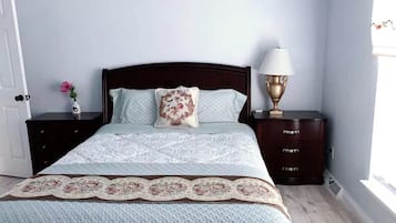 A bedroom with a bed, nightstands, a lamp, and a window.