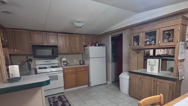 Una cocina compacta con armarios de madera, un microondas, una estufa y un refrigerador.