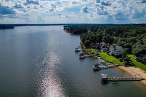 Une propriété au bord du lac, dotée d’un quai, d’une grande maison et d’une pelouse bien entretenue.