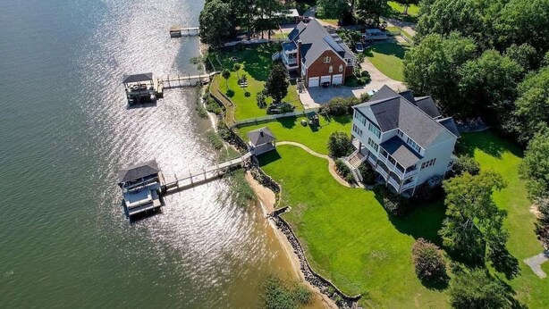 Une maison avec une jetée qui s’avance sur un lac, entourée d’une végétation luxuriante.