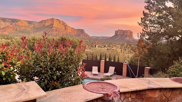 A patio with a stone wall, a small water feature, and a view of a mountain range. - Specials: Lux Escape | Pool, Hot Tub, Epic Views (Sedona)