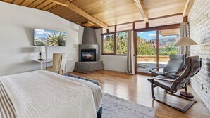 A bedroom with a bed, a fireplace, a TV, and a view of the outdoors. - Specials: Lux Escape | Pool, Hot Tub, Epic Views (Sedona)