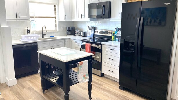 A modern kitchen with white cabinets, a black refrigerator, a microwave, and a dishwasher. - Minutes to Sanibel with Heated Pool, Tennis & Beach Gear (Fort Myers)