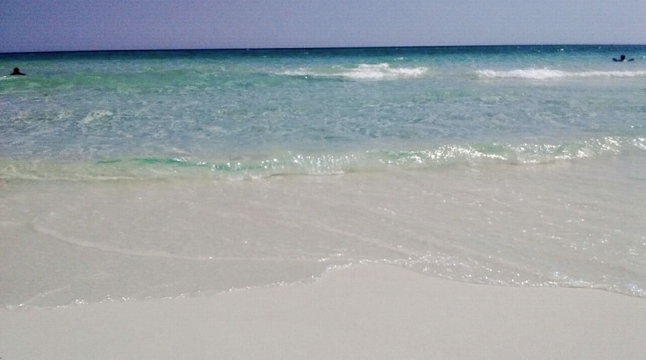 A beach with clear turquoise water and white sand.