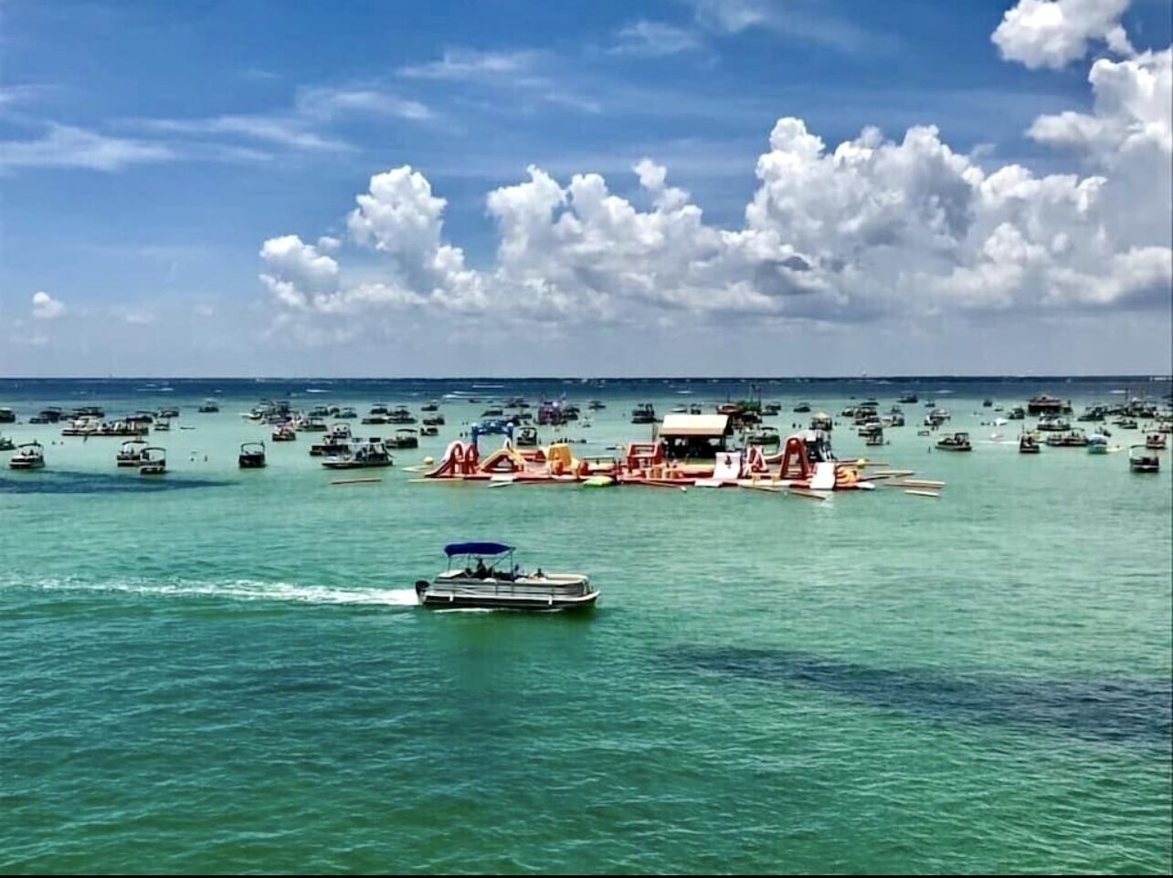 Un port de plaisance où sont amarrés de nombreux bateaux et yachts, un ciel dégagé et une eau calme.