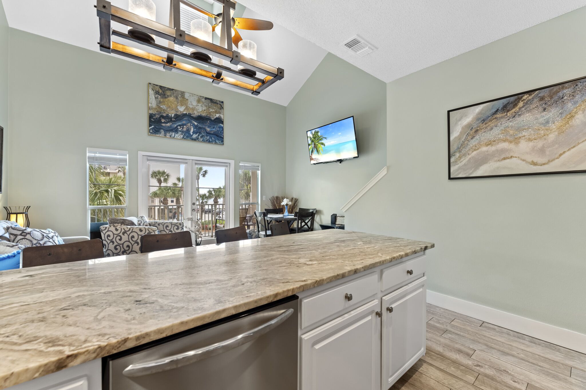 A spacious kitchen with a large island, a dining area with chairs, and a TV mounted on the wall.