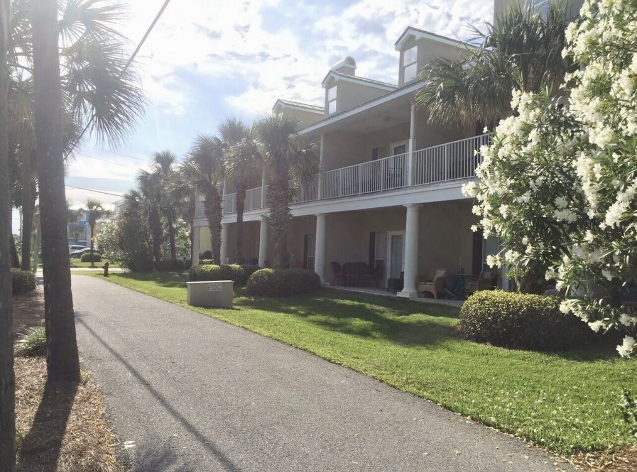A two-story building with a balcony, surrounded by well-maintained lawns and palm trees.