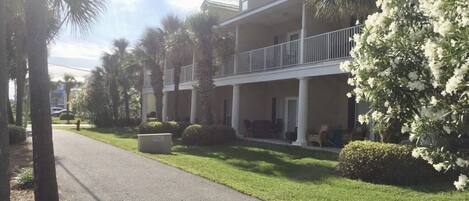 A two-story building with a balcony, surrounded by well-maintained lawns and palm trees.
