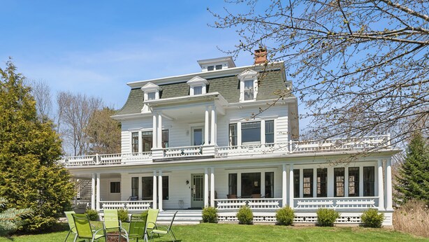 A two-story house with a porch, green chairs, and a well-maintained lawn. - A historic treasure in Southern Maine, very unique and spacious   (Biddeford)