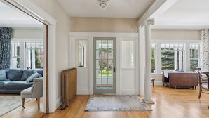 A spacious living room with hardwood floors, a grey sofa, a wooden coffee table, and a dining area with a table and chairs. - A historic treasure in Southern Maine, very unique and spacious   (Biddeford)
