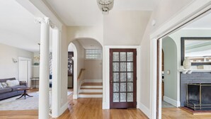 A spacious hallway with wooden flooring, white columns, a staircase, and a fireplace. - A historic treasure in Southern Maine, very unique and spacious   (Biddeford)