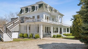 A large, two-story house with a covered porch and a staircase leading to the upper level. - A historic treasure in Southern Maine, very unique and spacious   (Biddeford)