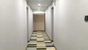 Ein Flur mit Schachbrettmuster, weißen Wänden und einer Tür am Ende.