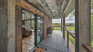 Una terraza de madera con un ventanal de vidrio que da a una habitación amoblada.
