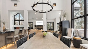 A spacious dining area with a long table, chairs, and a chandelier. - Larkspur Lodge - walk to ski lift and BC Village (Beaver Creek)
