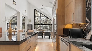 A modern kitchen with a large island, wooden cabinets, and a view of the outdoors. - Larkspur Lodge - walk to ski lift and BC Village (Beaver Creek)