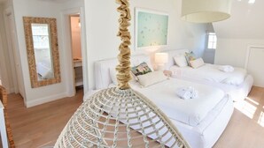 A spacious bedroom with a large bed, a hanging chair, and a mirror. - Steps to Oyster Pond Private Dock! (Chatham)