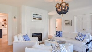 A modern living room with a white fireplace, white sofas, and a chandelier. - Steps to Oyster Pond Private Dock! (Chatham)