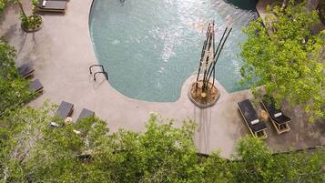 Relax by the serene pool surrounded by lush greenery and comfortable seating options.