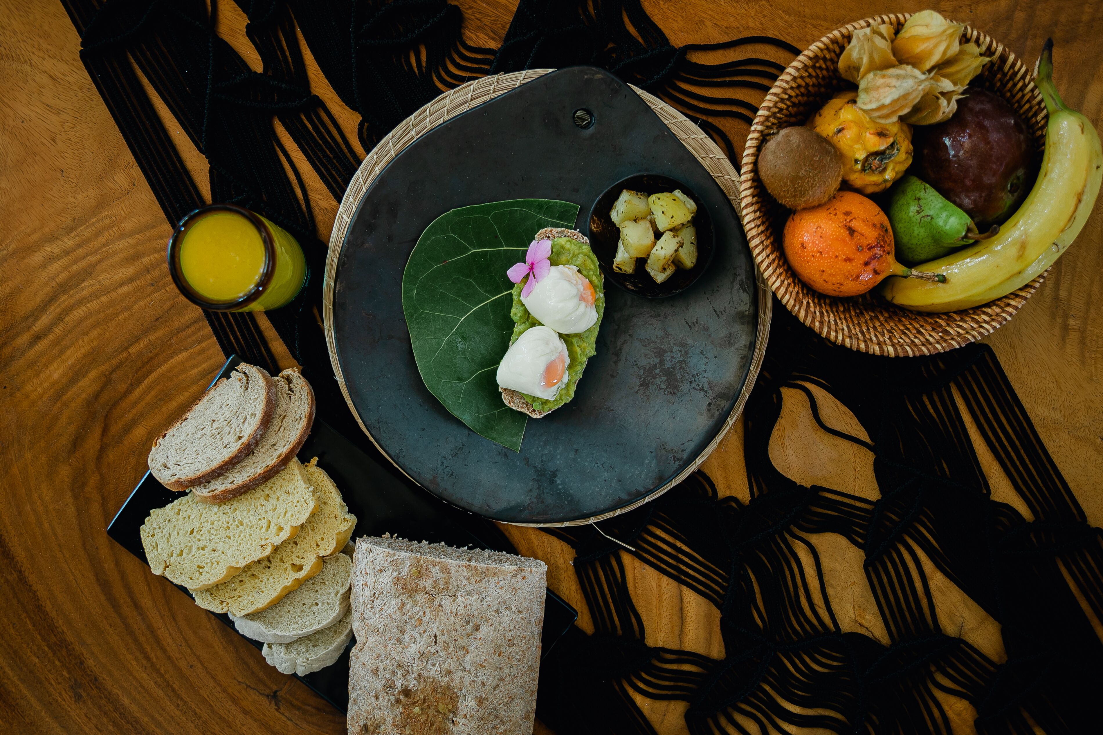 A table with a plate of food, a bowl of fruit, and a glass of juice.