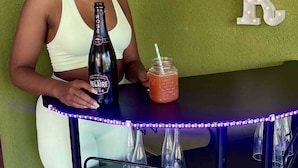 A bar area with a green wall, illuminated letters spelling "BAR", a bottle of rosé wine, and a mason jar with a drink. - Penthouse villa on the beach, chef services available- extra cost.  (Ocho Rios)