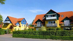 Una hilera de casas coloridas con tejados rojos y balcones, rodeadas de setos cuidados.
