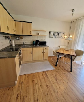 A compact kitchen with wooden cabinets, a countertop, and a dining area with a table and chairs.