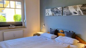 Un dormitorio con cama, ventana, radiador y decoración en la pared.