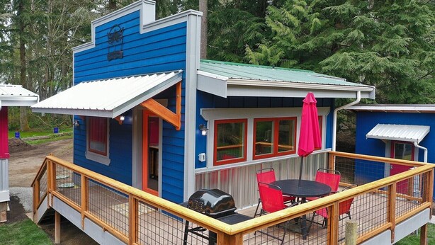 A small, blue cabin with a deck and outdoor seating area. - The Ridge at Langley: Villa Oscar (Langley)