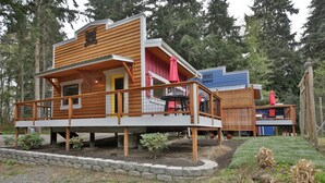 A cabin with a wooden deck, a small porch, and a red umbrella. - The Ridge at Langley: Villa Oscar (Langley)