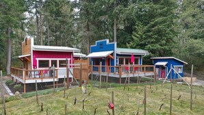 A row of colorful cabins with wooden decks and fenced yards, surrounded by trees. - The Ridge at Langley: Villa Oscar (Langley)