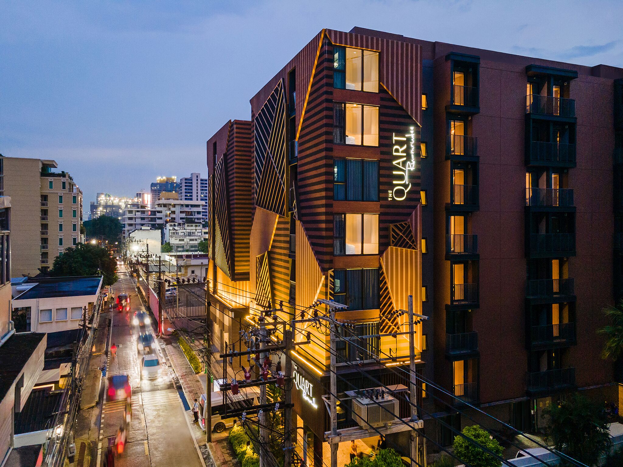 Um edifício moderno com fachada geométrica distinta, várias varandas e um letreiro chamativo com a palavra 