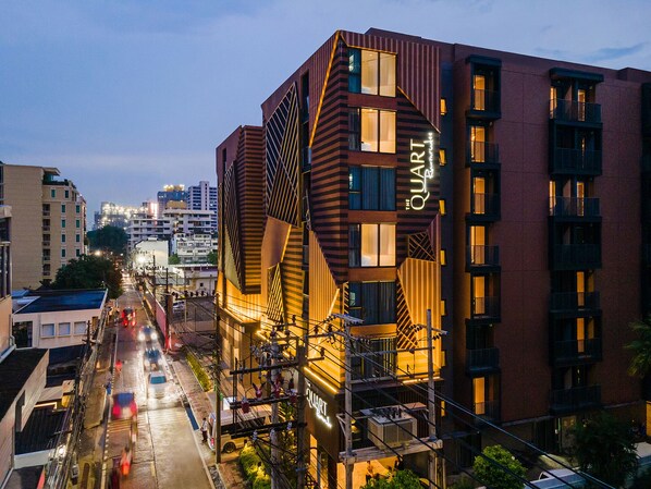 A modern building with a unique geometric facade, multiple balconies, and a prominent sign reading "QUART".