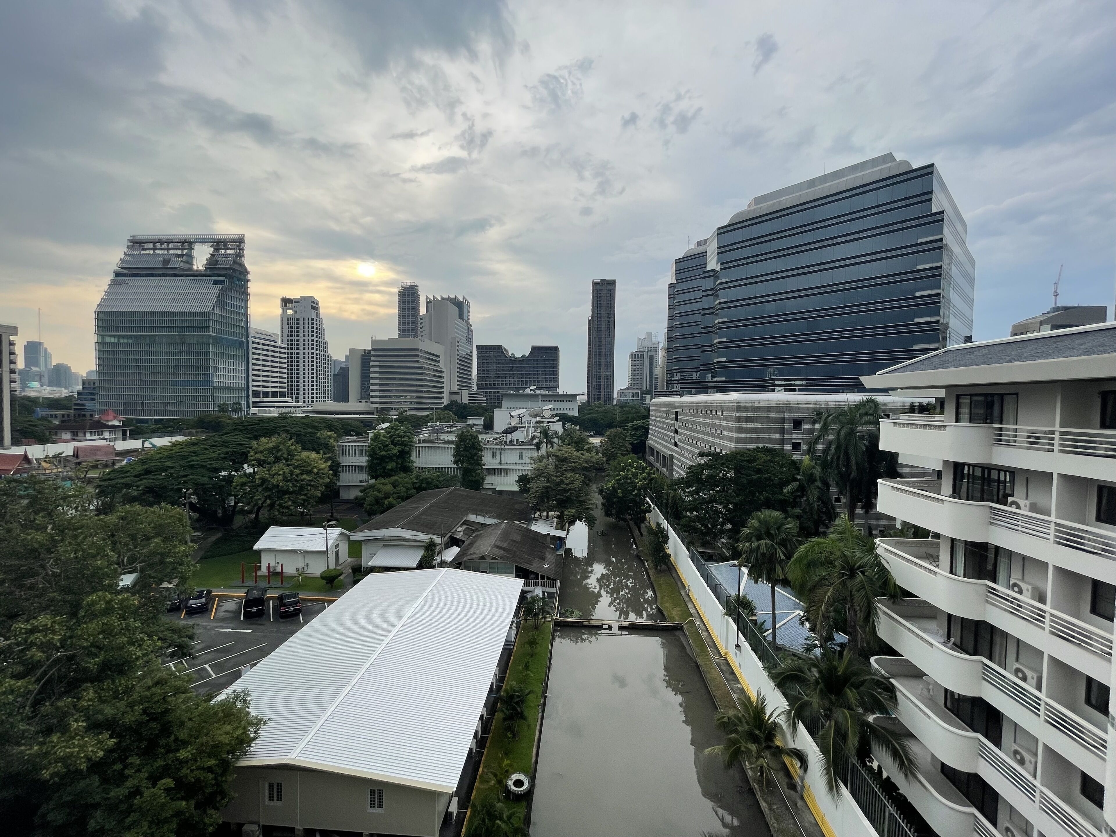 A cityscape with modern buildings, a parking lot, and a green area with trees.