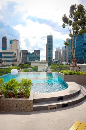 Ein Pool auf dem Dach mit Blick auf die Stadt, umgeben von Grünflächen und modernen Gebäuden.