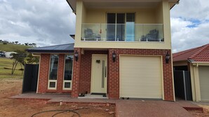 A two-story house with a balcony, a garage, and a brick facade. - Stylish house in the middle of the Links Lady Bay Golf Course (Normanville)