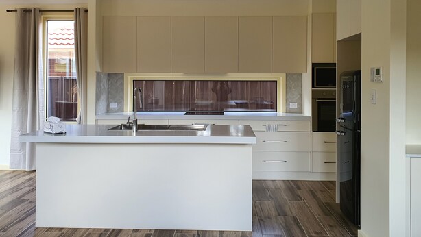 A modern kitchen with a central island, built-in appliances, and a large window. - Stylish house in the middle of the Links Lady Bay Golf Course (Normanville)
