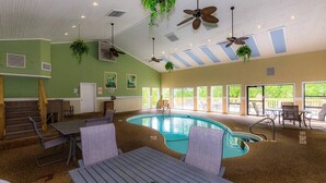 An indoor swimming pool area with ceiling fans, seating, and large windows.