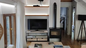 A modern living room with a wooden ceiling, a large flat-screen TV, a fireplace, and a cozy seating area. - Bamboo I - tucasaenlospirineos (Escarrilla)