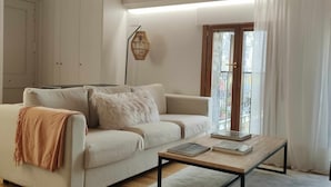 A modern living room with a wooden ceiling, a white sofa, a coffee table, and a large window with curtains. - Bamboo I - tucasaenlospirineos (Escarrilla)