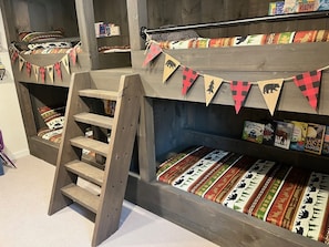 A bunk bed with a ladder, decorated with animal-themed bunting and books on the shelves.