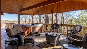A covered outdoor deck with wicker furniture, a hot tub, and a glass-top table. - Stress Re-Leaf - Blowing Rock Cabin with great view, hot tub, pool table (Lenoir)