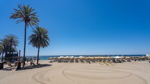 A beach with palm trees, umbrellas, and a playground.