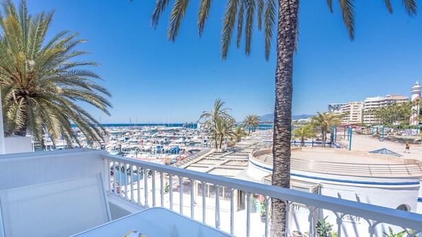 A balcony with a view of a marina, palm trees, and a stage area.