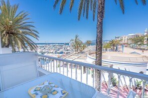 Un balcon offrant une vue sur un port de plaisance, des palmiers et une scène.