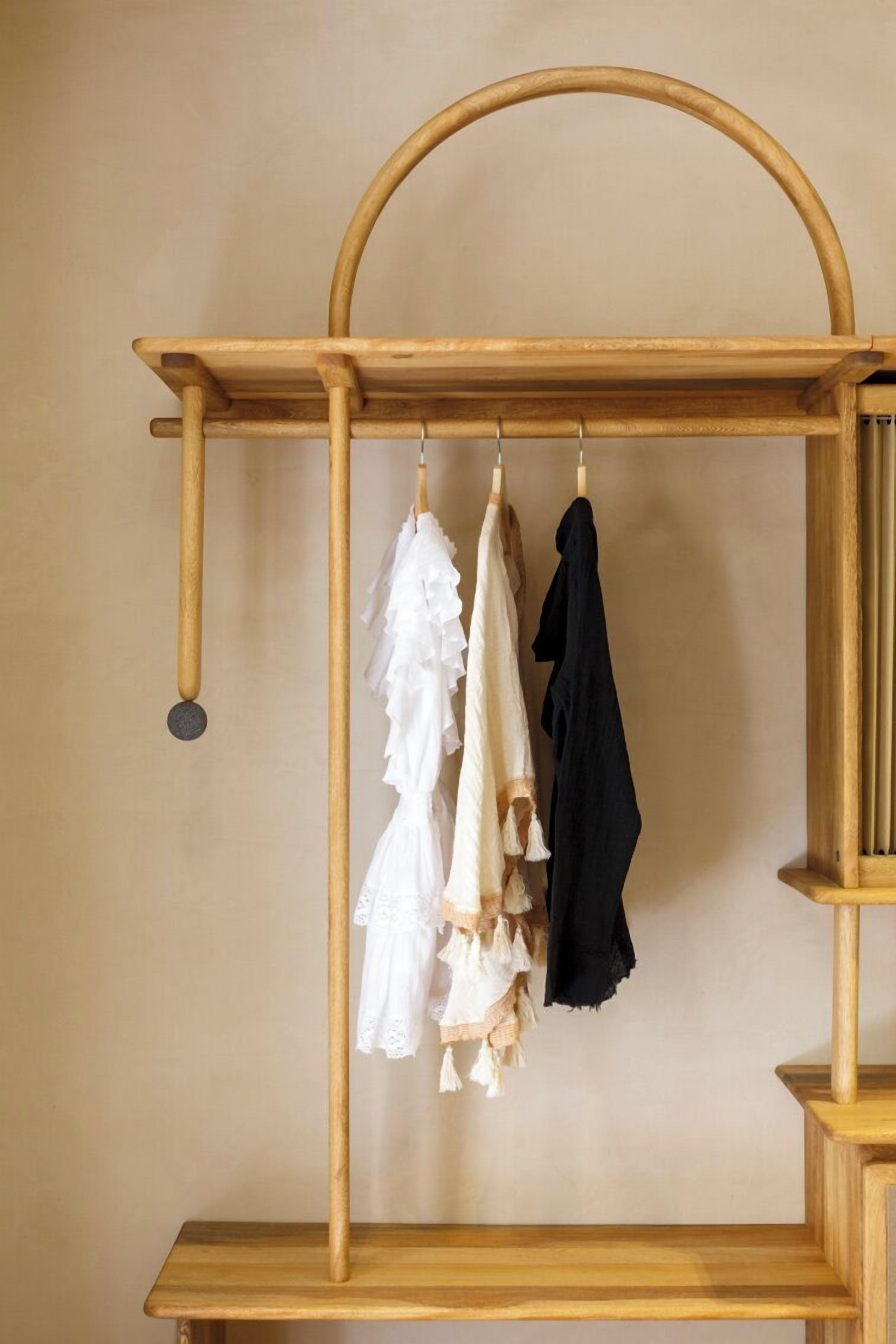 A wooden clothing rack with three garments hanging.