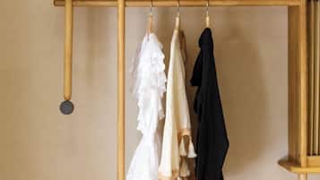 A wooden clothing rack with three garments hanging.