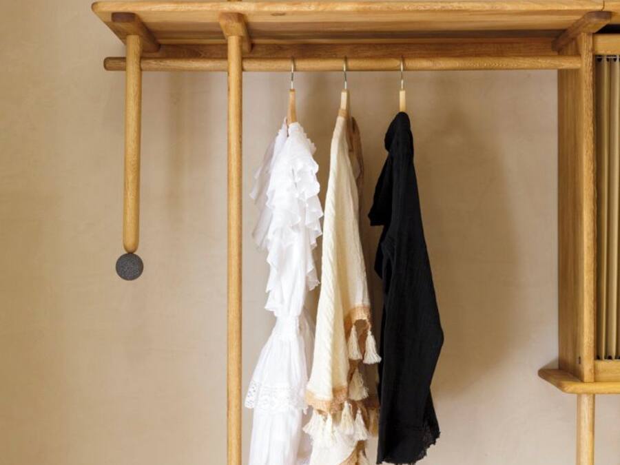 A wooden clothing rack with three garments hanging.