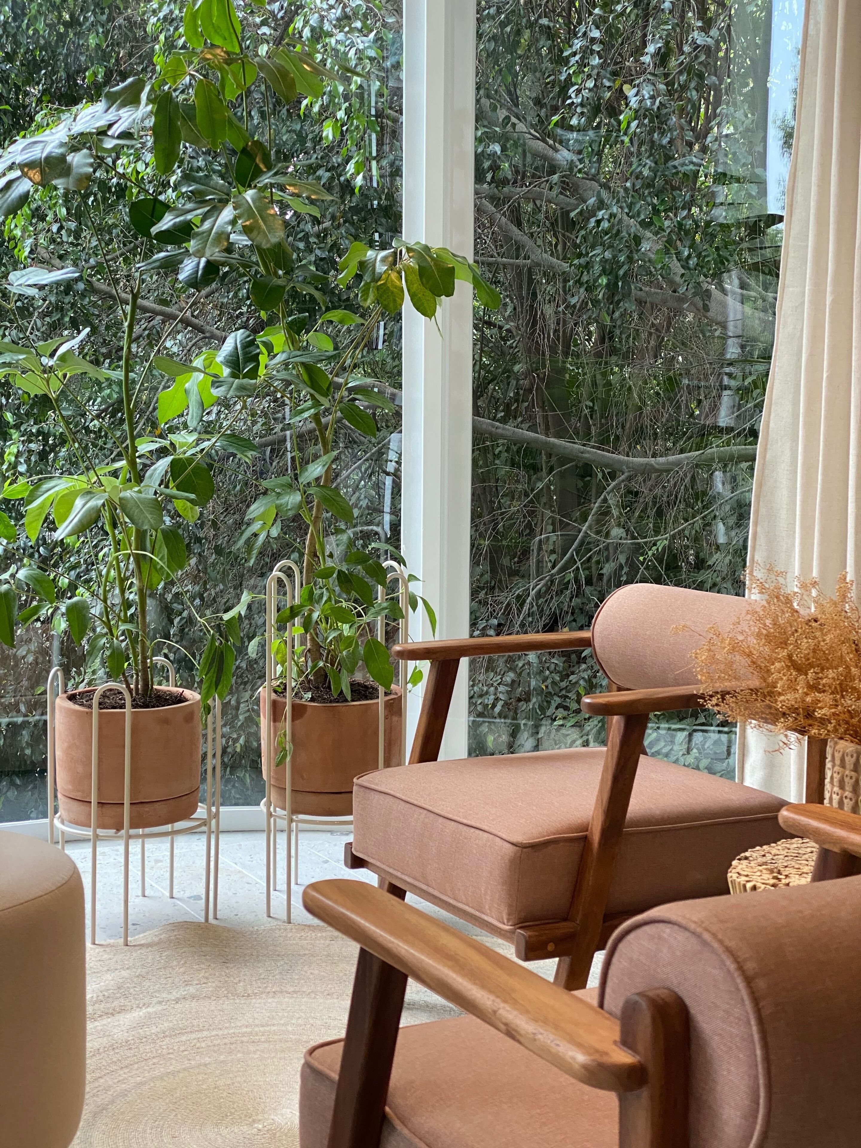 A cozy seating area with a view of a lush garden through large windows.